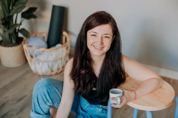 Frau mit Tasse an einem kleinen Tisch in ihrem Arbeitsraum